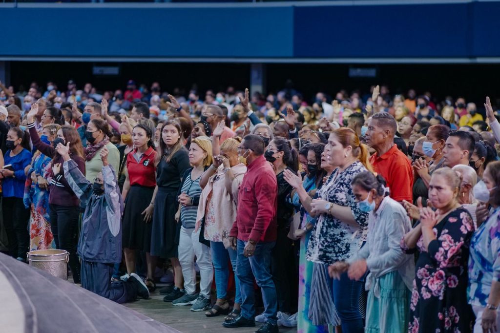 A large, diverse crowd attending an indoor event, full of energy and engaged.